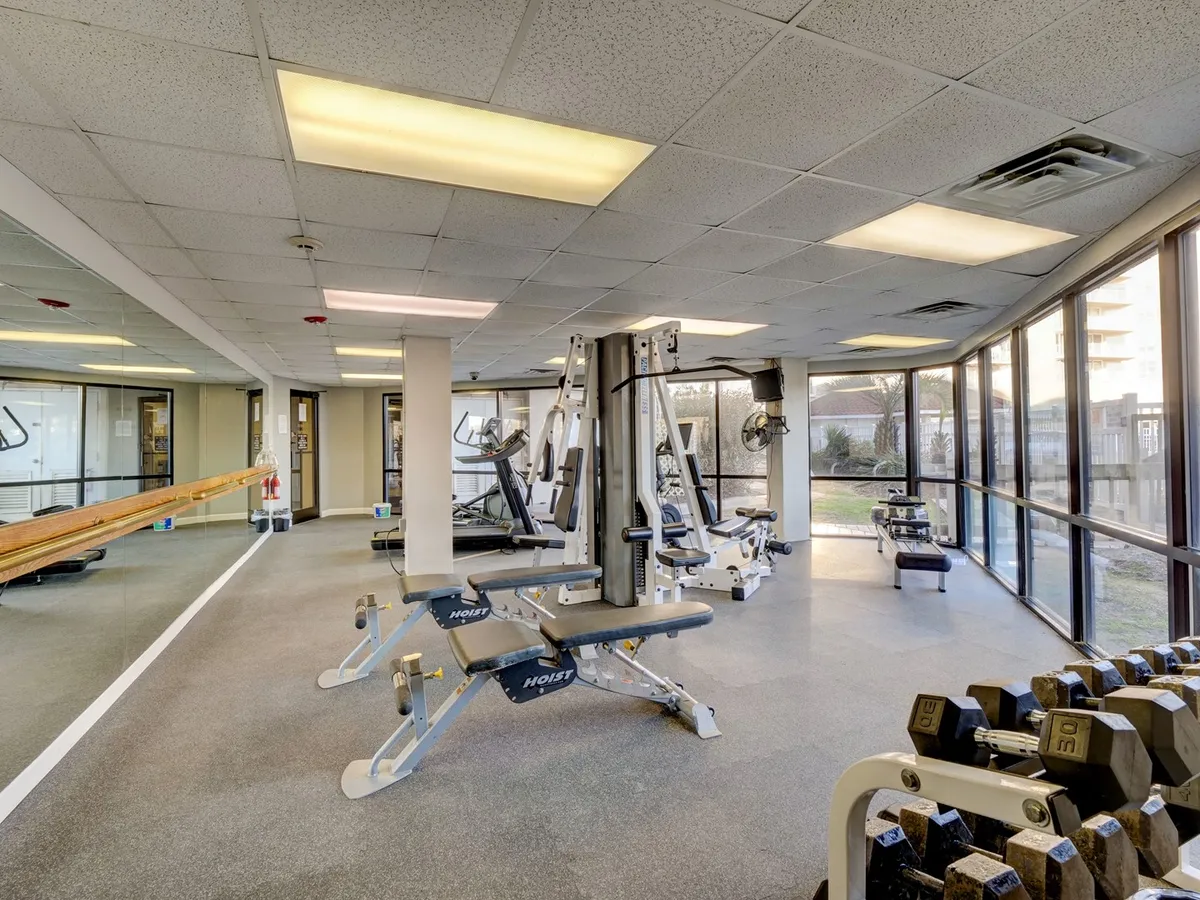 A well-equipped fitness center with modern exercise machines, free weights, and large windows letting in natural light, creating an energetic and inviting environment for wellness and activity.