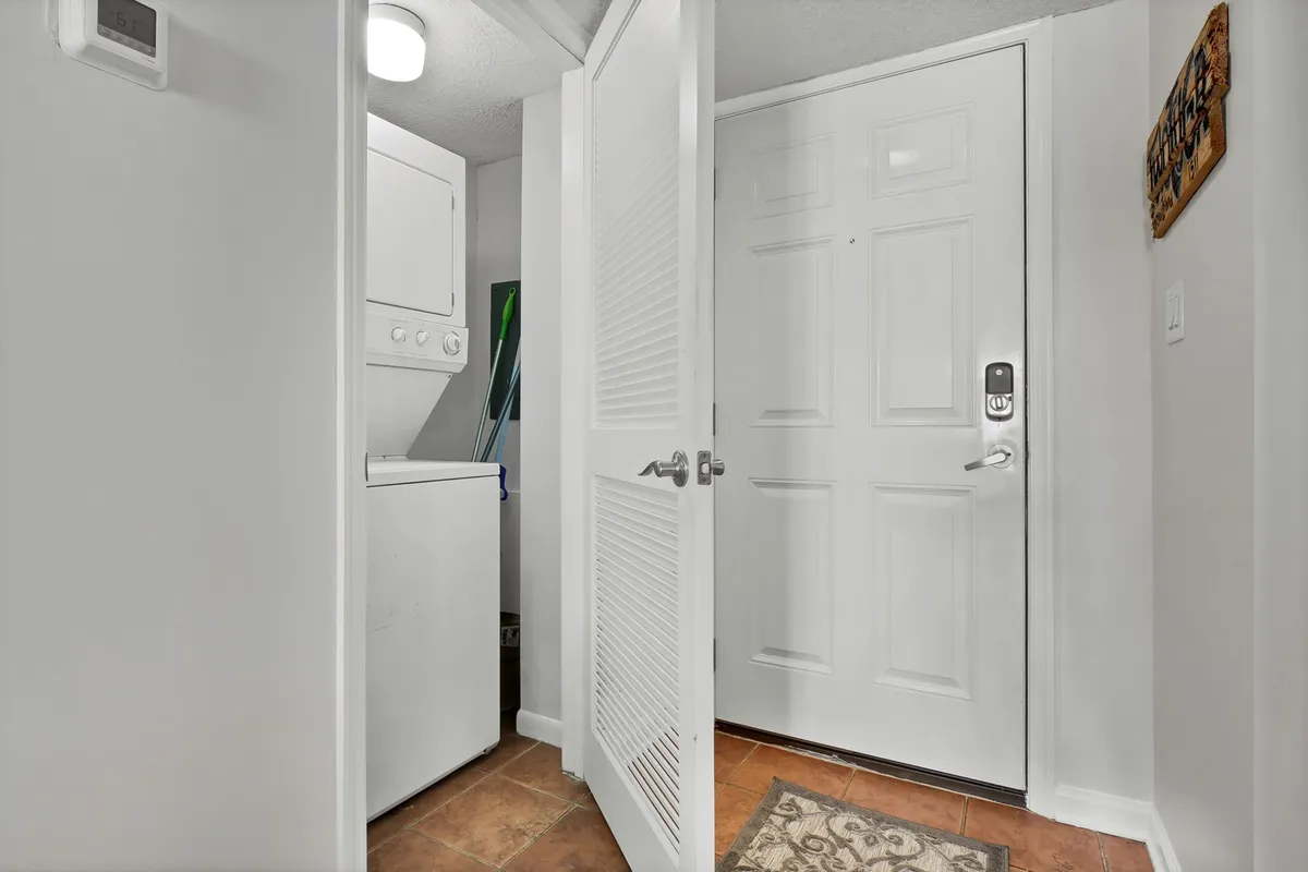 A practical laundry area located by the front door, featuring a washer and dryer, a welcome mat, and storage space. The area is functional yet tidy, supporting the needs of longer family stays.